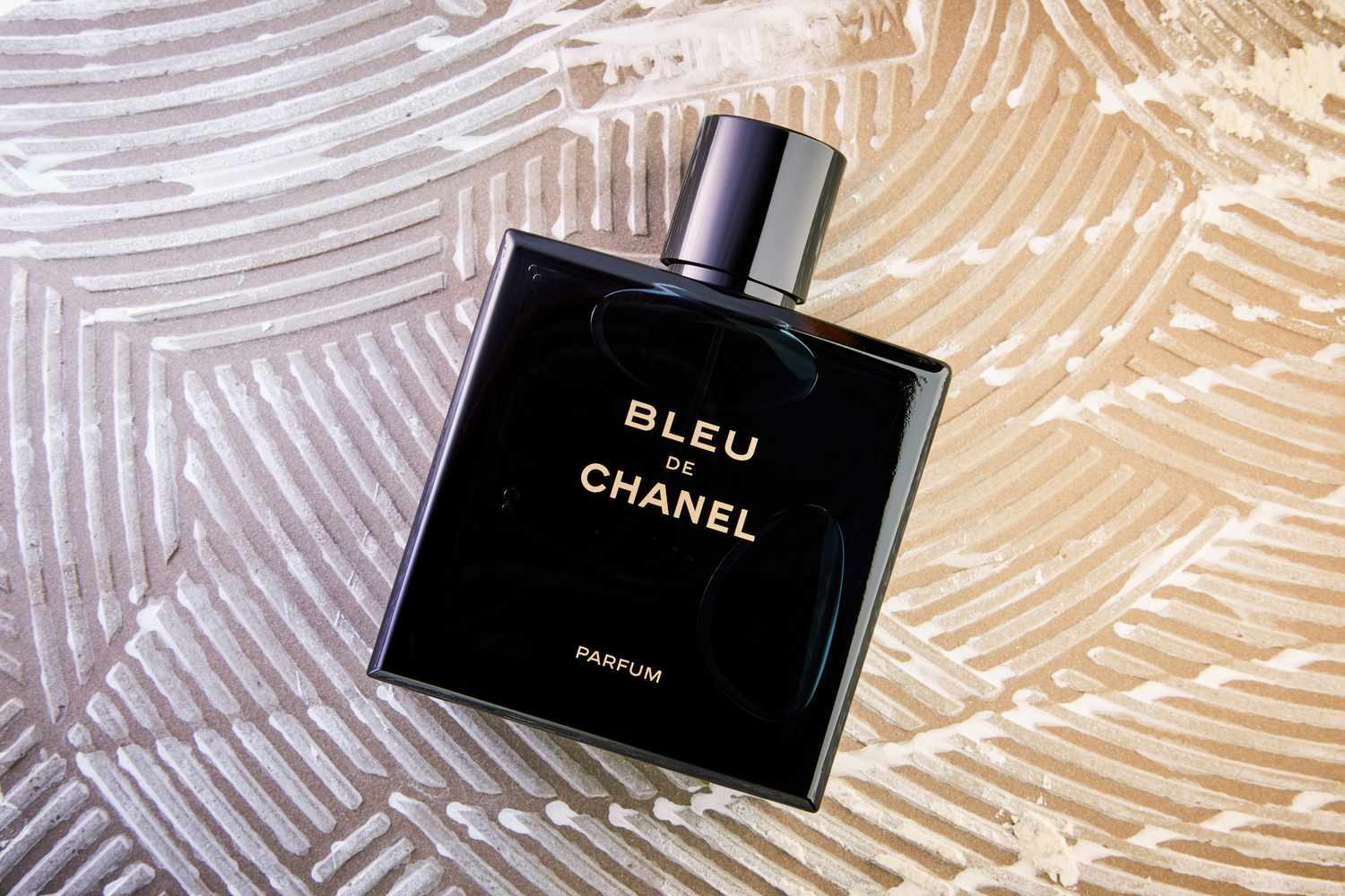 A bottle of Chanel Bleu de Chanel Parfum on a textured background